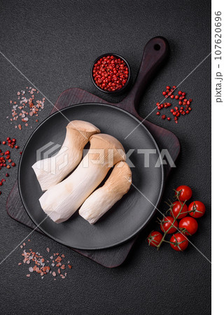 Pleurotus eryngii mushrooms on a dark concrete background 107620696