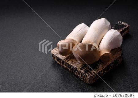 Pleurotus eryngii mushrooms on a dark concrete background 107620697
