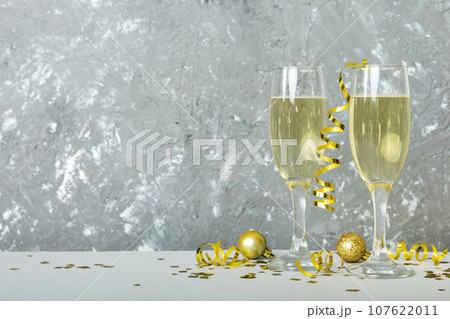 Champagne glasses and christmas decor on colored holiday background. Flat lay New Year decorations 107622011