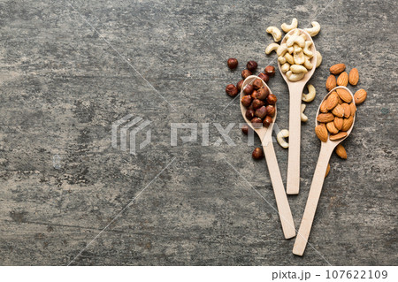 Assortment of nuts in wooden spoon on colored table. Cashew, hazelnuts, walnuts, almonds. Mix of nuts Top view with copy space 107622109