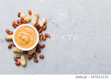 Bowl of peanut butter and peanuts on table background. top view with copy space. Creamy peanut pasta in small bowl Bowl of peanut butter and peanuts on table background. top view with copy space. Creamy peanut pasta in small bowl 107622210