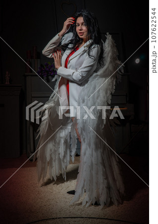 Portrait of a cute smiling angel woman posing in pink dress with wings on her back. Portrait of a cute smiling angel woman posing in pink dress with wings on her back. 107622544