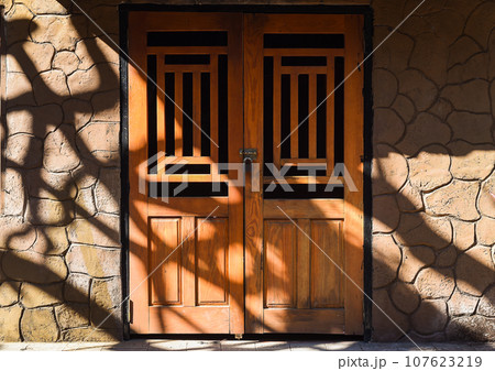 Closed wooden door with hanging door lock under sun rays Closed wooden door with hanging door lock under sun rays 107623219