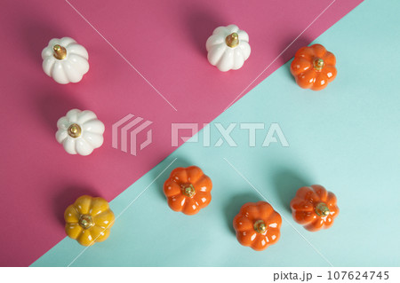 small ceramic pumpkins in different colors on a two-tone turquoise and fuschia pink background small ceramic pumpkins in different colors on a two-tone turquoise and fuschia pink background 107624745