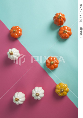 small ceramic pumpkins in different colors on a two-tone turquoise and fuschia pink background small ceramic pumpkins in different colors on a two-tone turquoise and fuschia pink background 107624746