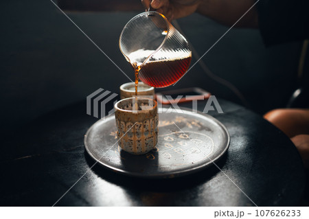 Black coffee is being poured into a ceramic mug. Black coffee is being poured into a ceramic mug. 107626233