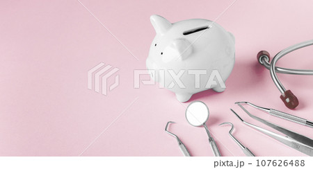 Piggy bank and dental tools on pink background, copy space 107626488