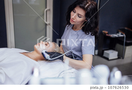 Closeup of face of beautiful relaxing girl undergoing hardware cosmetology procedure in spa 107626530