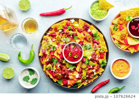 Loaded nachos. Mexican nacho chips with beef, overhead flat lay shot 107626624