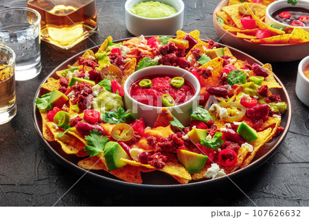Loaded nachos. Mexican nacho chips with beef, with guacamole sauce Loaded nachos. Mexican nacho chips with beef, with guacamole sauce 107626632