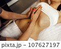 Close up of young woman getting belly massage in spa salon 107627197