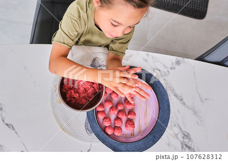 A girl is preparing meatballs in the kitchen. A girl is preparing meatballs in the kitchen. 107628312