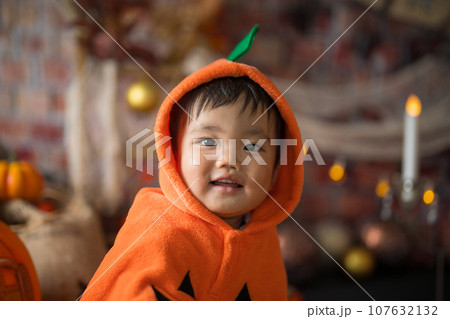 10月にハロウィンのフォトセットに囲まれて楽しそうな笑顔を見せる生後11か月の赤ちゃん 107632132
