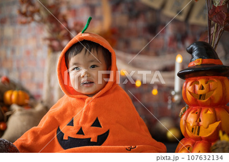 10月にハロウィンのフォトセットに囲まれて楽しそうな笑顔を見せる生後11か月の赤ちゃん 107632134