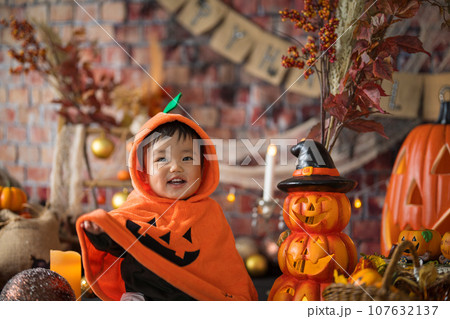 10月にハロウィンのフォトセットに囲まれて楽しそうな笑顔を見せる生後11か月の赤ちゃん 107632137