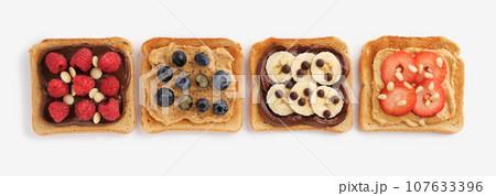 Sweet toasts with raspberries, banana, strawberries, blueberries on light background. Flatly. Sweet toasts with raspberries, banana, strawberries, blueberries on light background. Flatly. 107633396