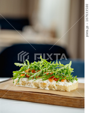 Tasty bruschetta with salmon and arugula on restaurant table in interior 107633580