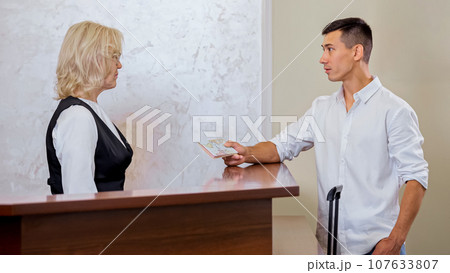 Young man handing over passport to find reserved hotel room 107633807