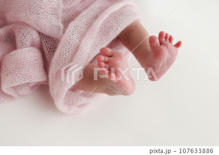 Close-up of tiny, cute, bare toes, heels and feet of a newborn girl, boy. Baby foot on pink soft coverlet, blanket. Detail of a newborn baby legs. Macro horizontal professional studio photo.  107633886