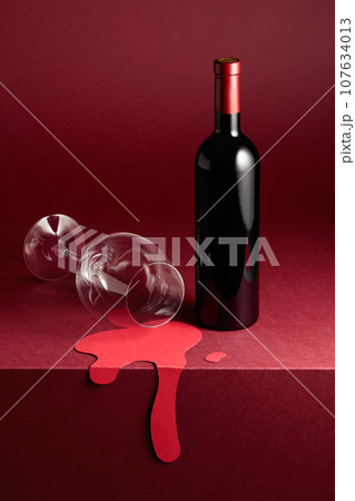Bottle and glass of red wine on a red background. Bottle and glass of red wine on a red background. 107634013