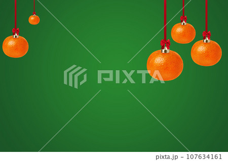 Tangerine as a Christmas ornament on green background with copy space. Creative Christmas greeting card. 107634161