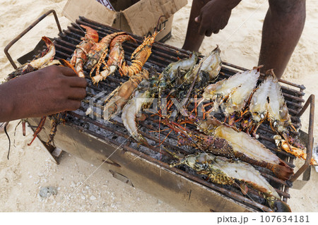 Lobsters and prawns cooked on small grill at the beach 107634181