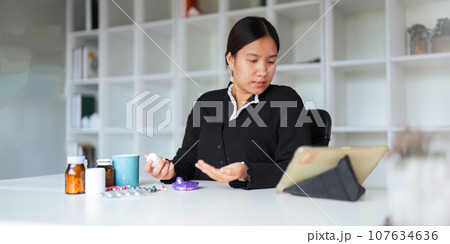 Health care asian young woman using tablet for search prescription on bottle medicine, pill label text about information online, instruction side effects, pharmacy medicament concept 107634636