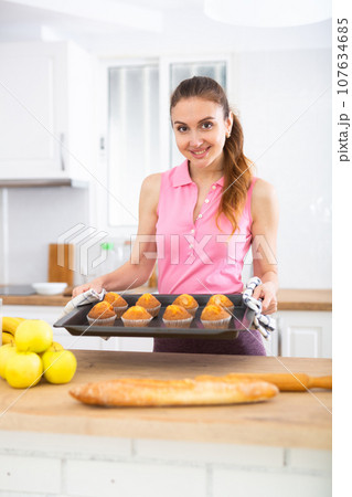 Portrait of cheerful housewife with cupcakes 107634685