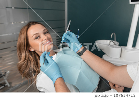 The woman receives high-quality care and treatment in a modern medical center staffed by professional dentists. The dental clinic performs high-quality teeth whitening, giving your smile a natural The woman receives high-quality care and treatment in a modern medical center staffed by professional dentists. The dental clinic performs high-quality teeth whitening, giving your smile a natural 107634715