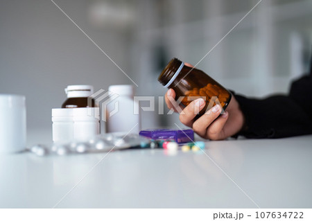 Woman hold bottle of drug tablet painkiller or vitamin supplement reading label ready to organizing medicine at home. medication healthcare concept Woman hold bottle of drug tablet painkiller or vitamin supplement reading label ready to organizing medicine at home. medication healthcare concept 107634722