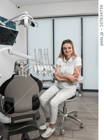 A dentist poses against the background of a dental chair, demonstrating professionalism and confidence. A dentist straightens teeth using modern technologies. 107634730