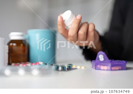 Woman hold bottle of drug tablet painkiller or vitamin supplement reading label ready to organizing medicine at home. medication healthcare concept Woman hold bottle of drug tablet painkiller or vitamin supplement reading label ready to organizing medicine at home. medication healthcare concept 107634749