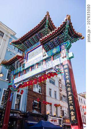 真っ青な青空の下のロンドンのチャイナタウンの豪華でたくさんの飾りがついた門 107635080