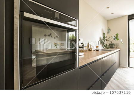 a modern kitchen with wood counter tops and stainless steel oven hoods on the wall behind it is an open door 107637110