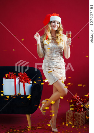 woman in santa hat with champagne in red room by sofa with confetti woman in santa hat with champagne in red room by sofa with confetti 107637461