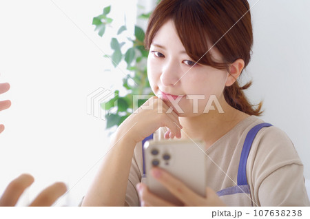 男性のスマホを見て複雑な表情をする女性 男性のスマホを見て複雑な表情をする女性 107638238