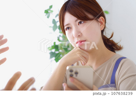 男性のスマホを見て複雑な表情をする女性 107638239