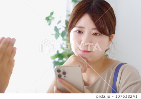 男性のスマホを見て複雑な表情をする女性 男性のスマホを見て複雑な表情をする女性 107638241