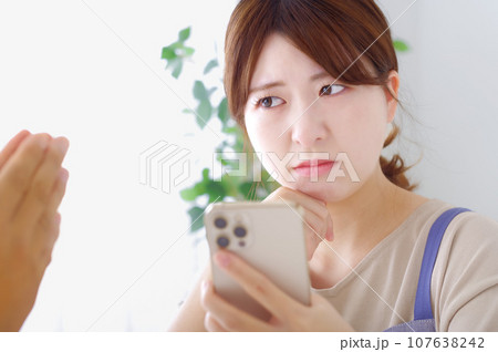 男性のスマホを見て複雑な表情をする女性 107638242