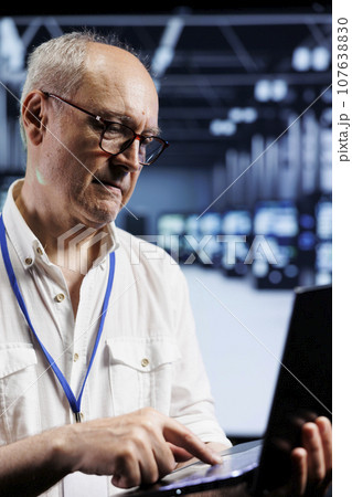 Computer scientist inspects supercomputers in data center, ensuring smooth performance. Knowledgeable specialist in server room monitoring energy consumption across units components using laptop Computer scientist inspects supercomputers in data center, ensuring smooth performance. Knowledgeable specialist in server room monitoring energy consumption across units components using laptop 107638830