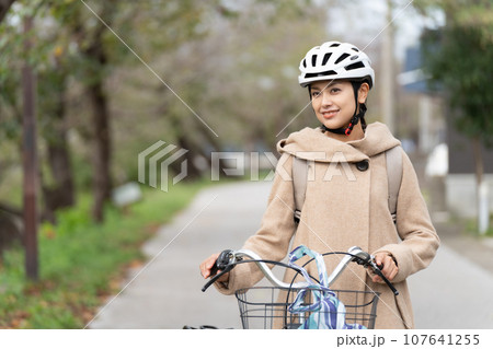 川沿いをリュックサックを背負ってキャメルロングコートを着て自転車を引いて歩く若い女性 上半身 川沿いをリュックサックを背負ってキャメルロングコートを着て自転車を引いて歩く若い女性 上半身 107641255