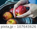 woman hand is cleaning red apple in bucket of water, closed up shot 107643626