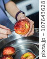 woman hand is cleaning red apple in bucket of water, closed up shot 107643628