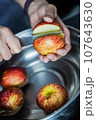 woman hand is cleaning red apple in bucket of water, closed up shot 107643630