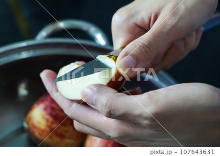 woman hand is cleaning red apple in bucket of water, closed up shot 107643631