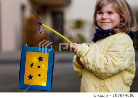 Little Preschool Kid Girl Holding Selfmade Traditional Lanterns with Candle for St. Martin Procession. Child Happy about Children and Family Parade in Kindergarten. German Tradition Martinsumzug. Little Preschool Kid Girl Holding Selfmade Traditional Lanterns with Candle for St. Martin Procession. Child Happy about Children and Family Parade in Kindergarten. German Tradition Martinsumzug. 107644686