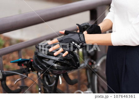 ロードバイクの脇でサイクリンググローブをはめる若い女性 107646361