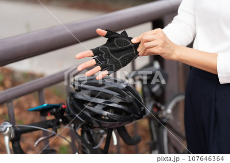 ロードバイクの脇でサイクリンググローブをはめる若い女性 ロードバイクの脇でサイクリンググローブをはめる若い女性 107646364