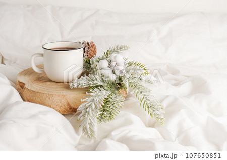 Coffee cup on the wood with Christmas decorations on white bed. Breakfast in bed. Winter morning 107650851