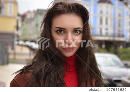 Portrait of a cute young woman in a brown autumn coat on the street with funny emotion 107651623